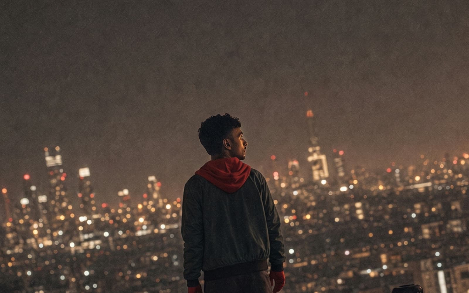 A figure on a rooftop above a lit city at night, a still from one of the videos